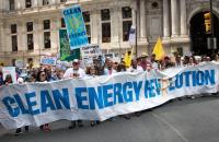 Demonstrators holding banner that reads "Clean Energy Revolution"