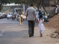 Father and daughter walk street hand in hand